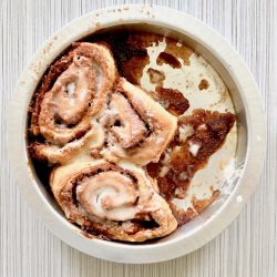 Amish Friendship Bread Cinnamon Rolls in a round pan on a light grey background