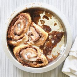 Amish Friendship Bread Cinnamon Rolls in a round pan on a light grey background