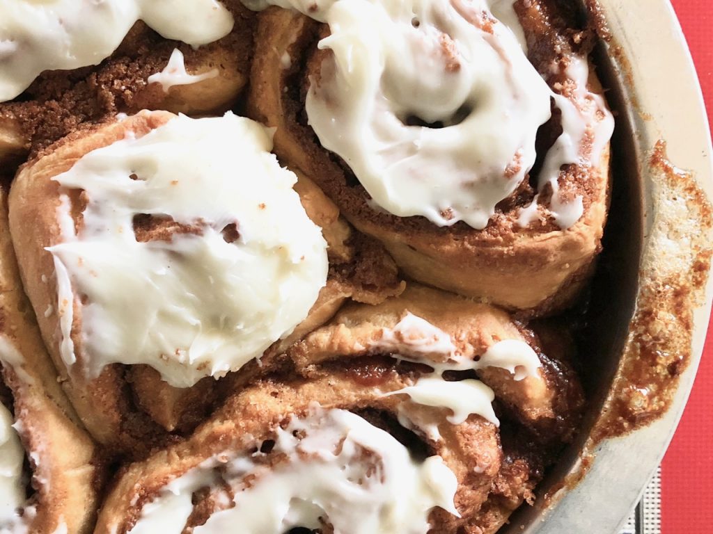 Amish Friendship Bread Cinnamon Rolls in a round pan on a light grey background