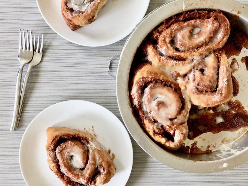 Amish Friendship Bread Cinnamon Rolls in a round panned two plates on a light grey background with two forks