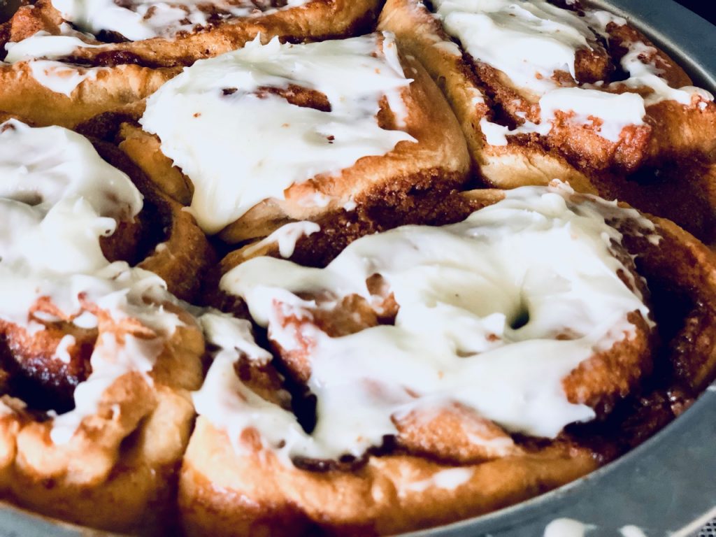 Amish Friendship Bread Cinnamon Rolls in a round pan on a light grey background