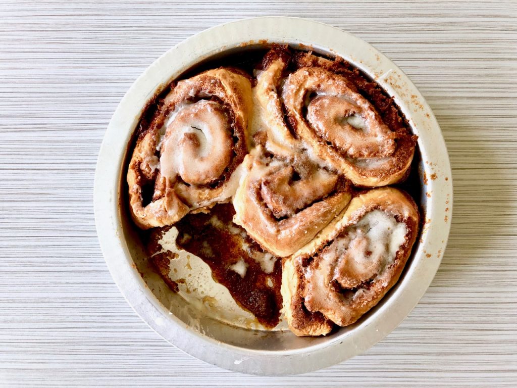 Amish Friendship Bread Cinnamon Rolls in a round pan on a light grey background