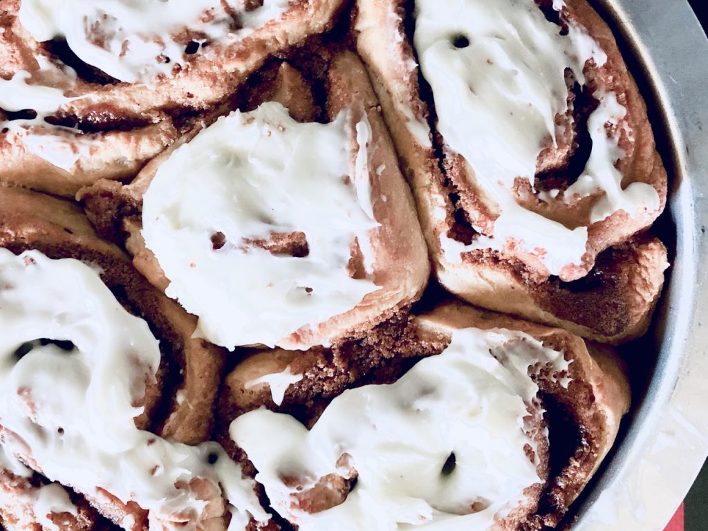 Amish Friendship Bread Cinnamon Rolls in a round pan on a light grey background