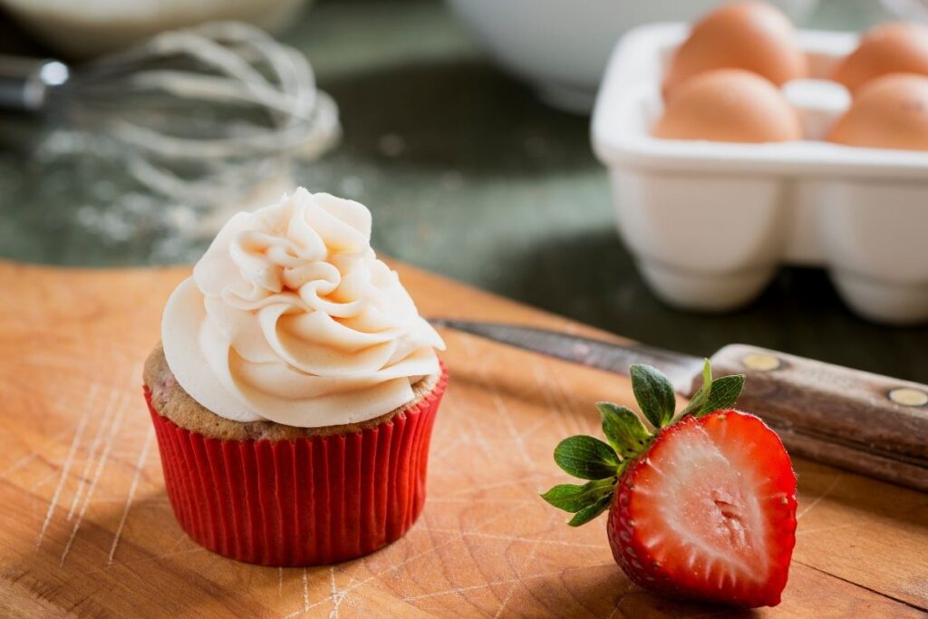 Amish Friendship Bread Strawberry Lemonade Cupcake with strawberry cut in half behind