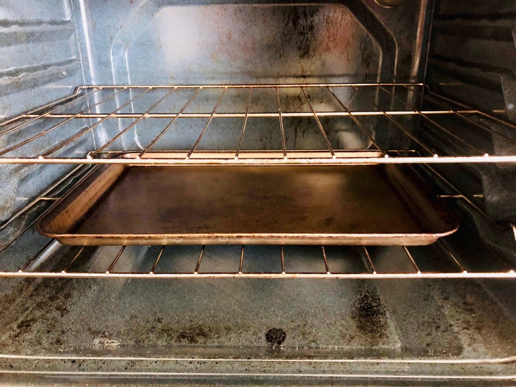 Open oven with baking pan on bottom rack