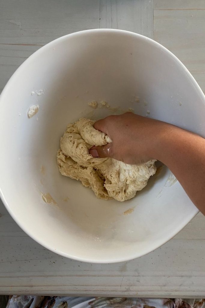 Hand kneading dough in a bowl.