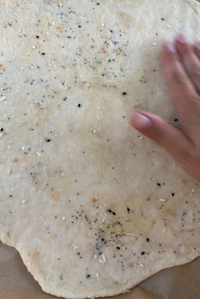 Spreading olive oil over rolled cracker dough.