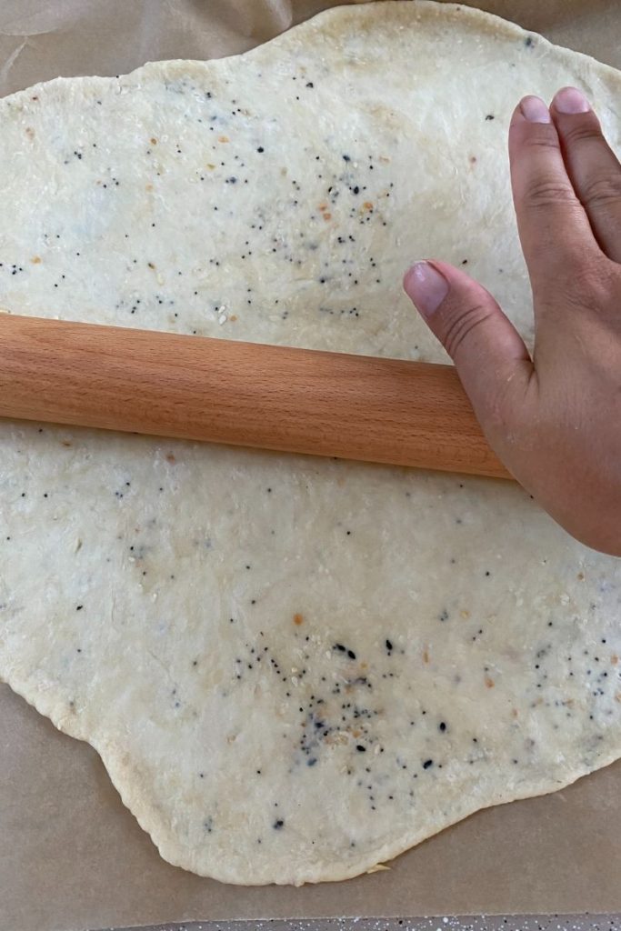 Wood rolling pin over dough on parchment.