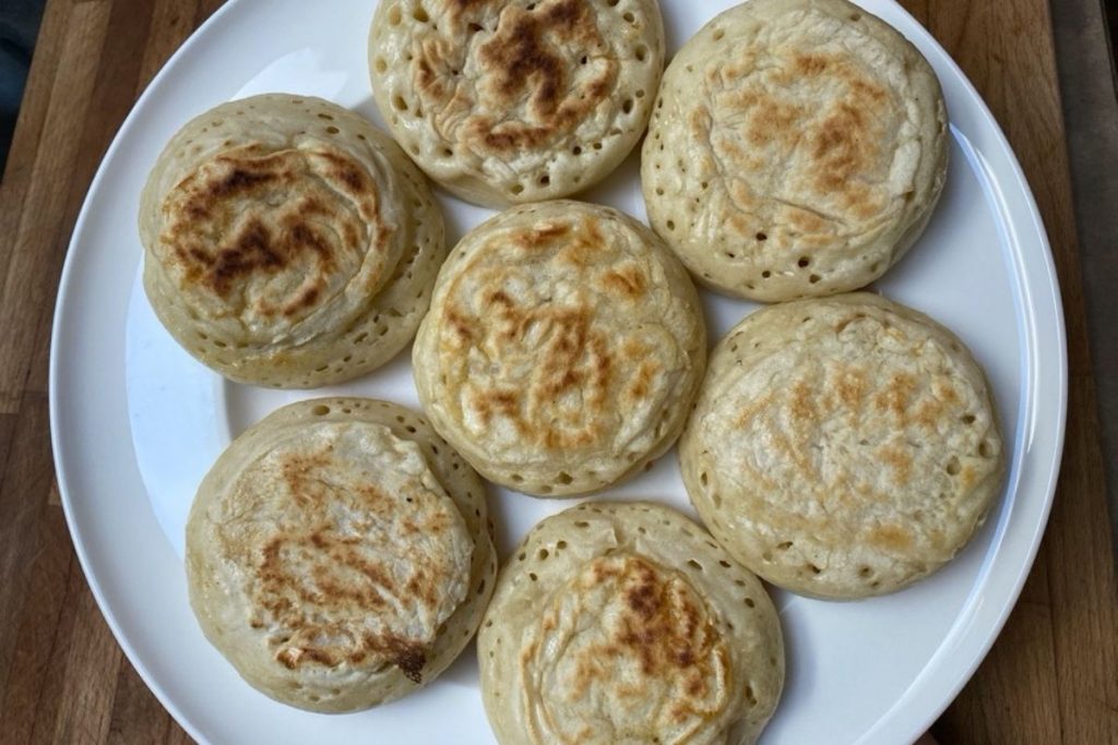 White plate filled with 7 sourdough crumpets.